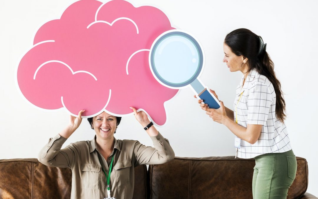 A print of a brain and a magnifier held by 2 woman