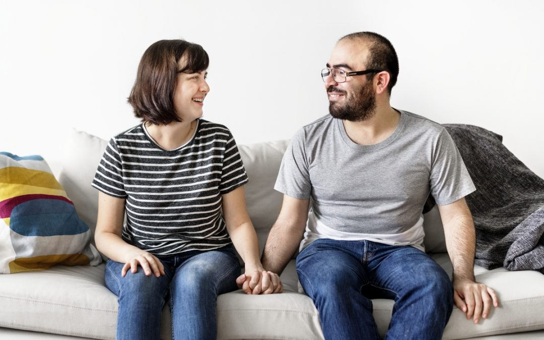 happy couple sitting at a couch staring at each other